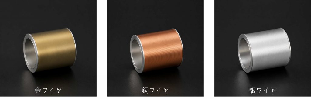 ボンディングに使用される3種類のワイヤスプール。左から金色の金ワイヤ、赤銅色の銅ワイヤ、銀白色の銀ワイヤが黒背景上に並んでいる
